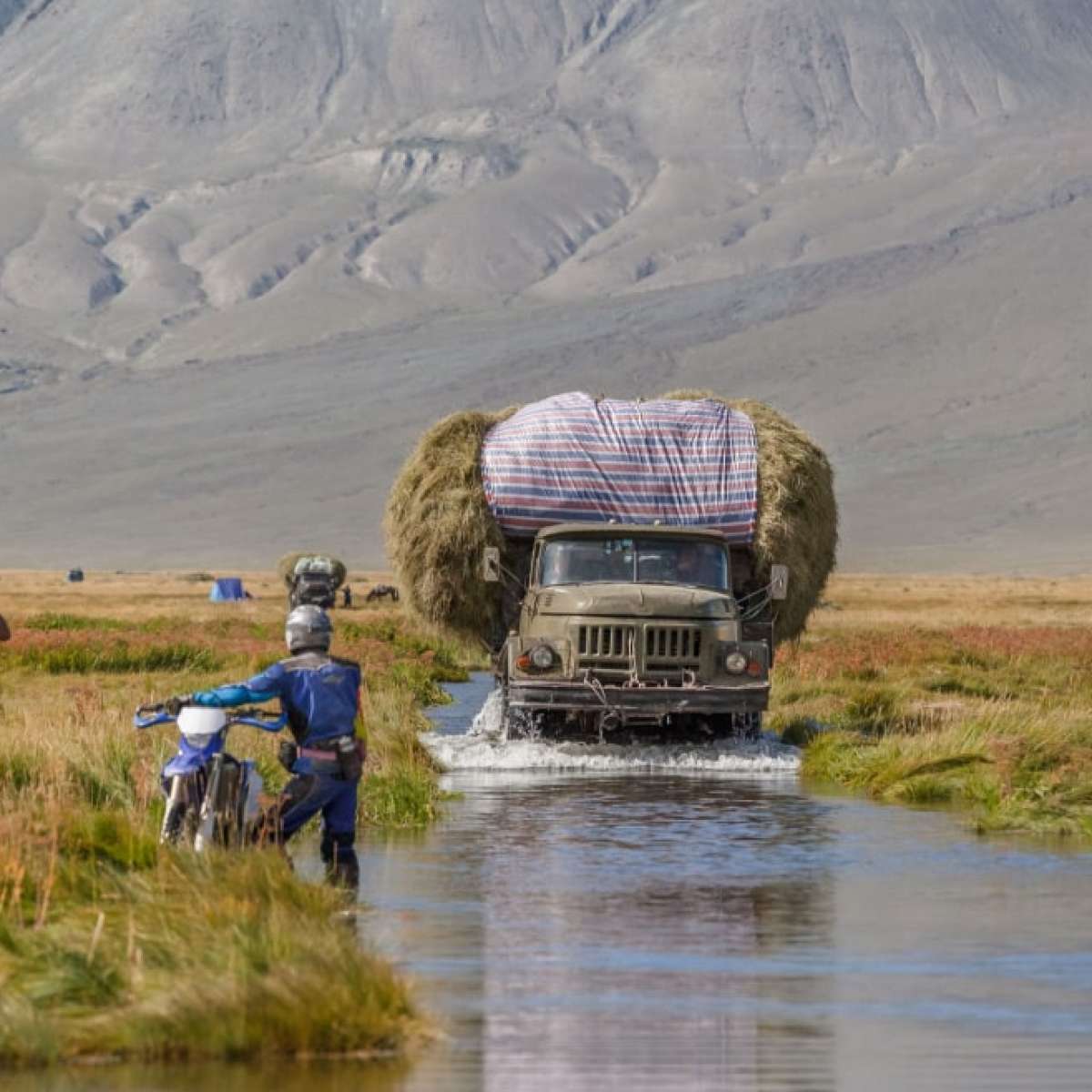 Truck carrying hay on a road covered with water after a flood. Altai, Mongolia.