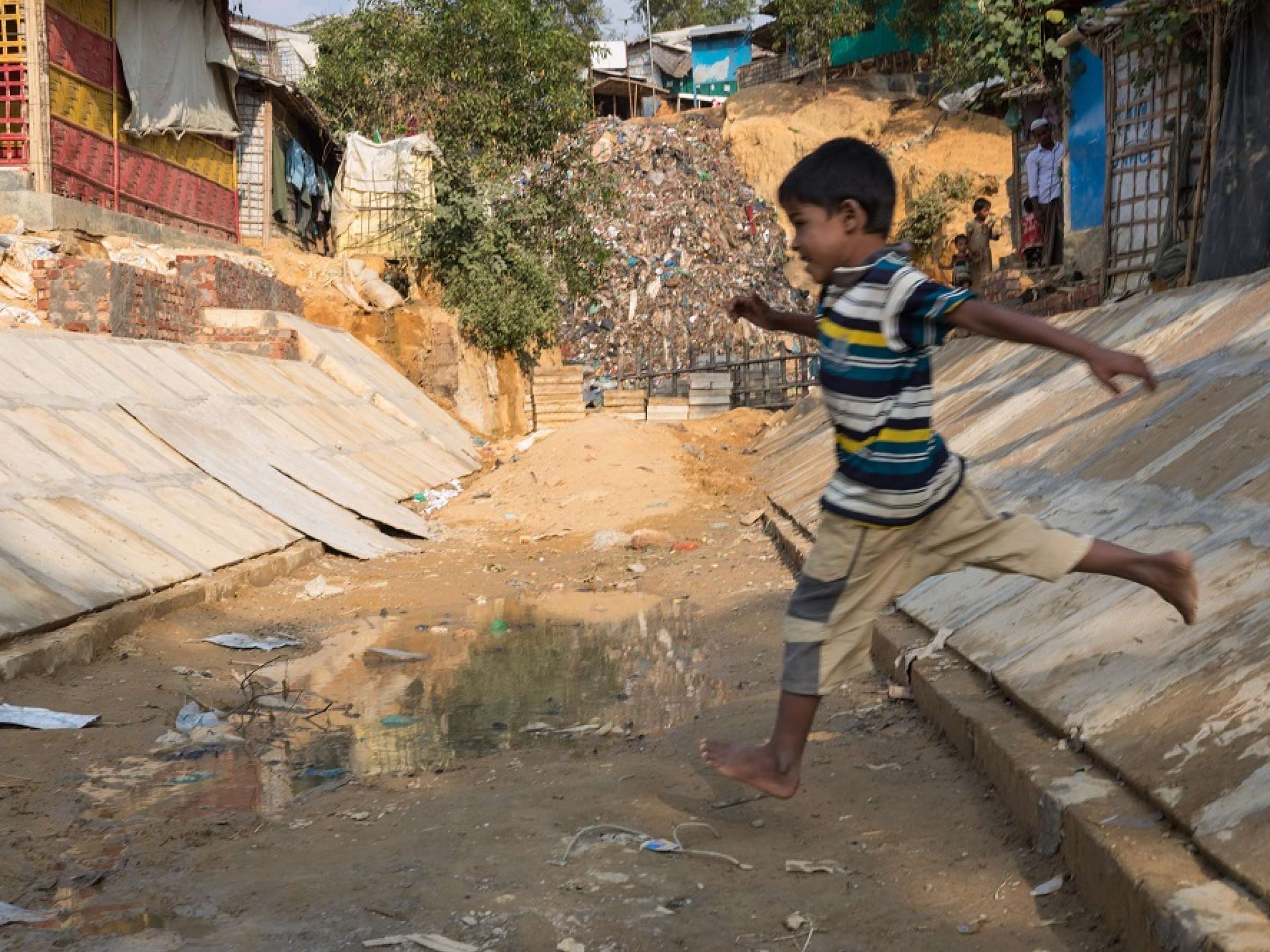 Child leaps over a drain in a camp in Bangladesh