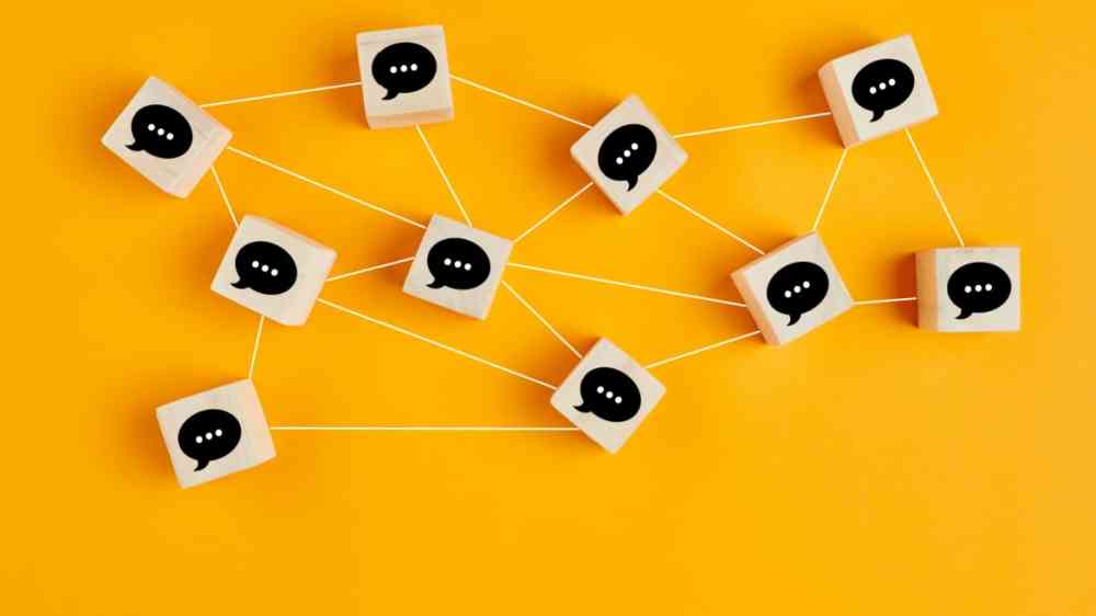 Concept of online communication or social networking. Wooden cubes with speech bubbles linked to each other with lines..