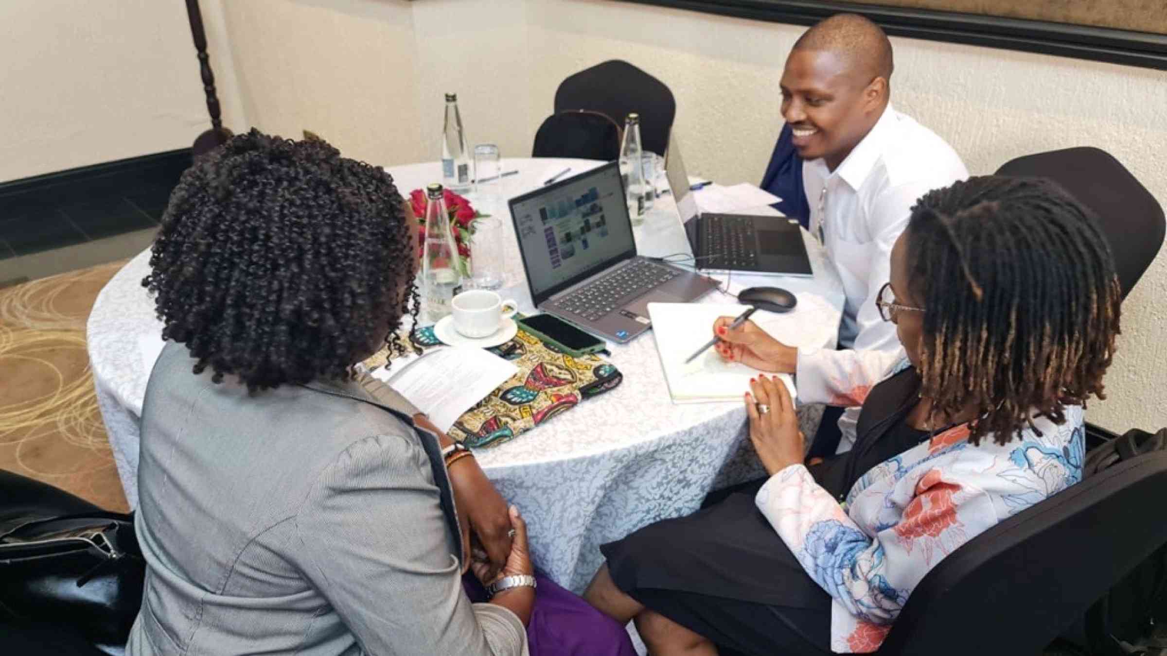 Three participants of the Transboundary Collaboration in the Horn of Africa workshop sat at a table, working together