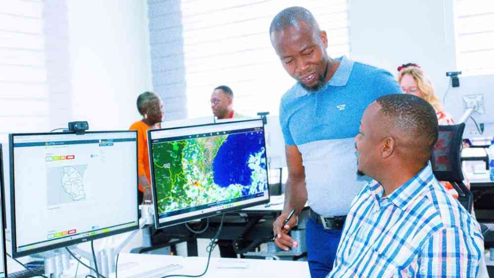 Two men talking in front of a computer in the Tanzanian Situation room