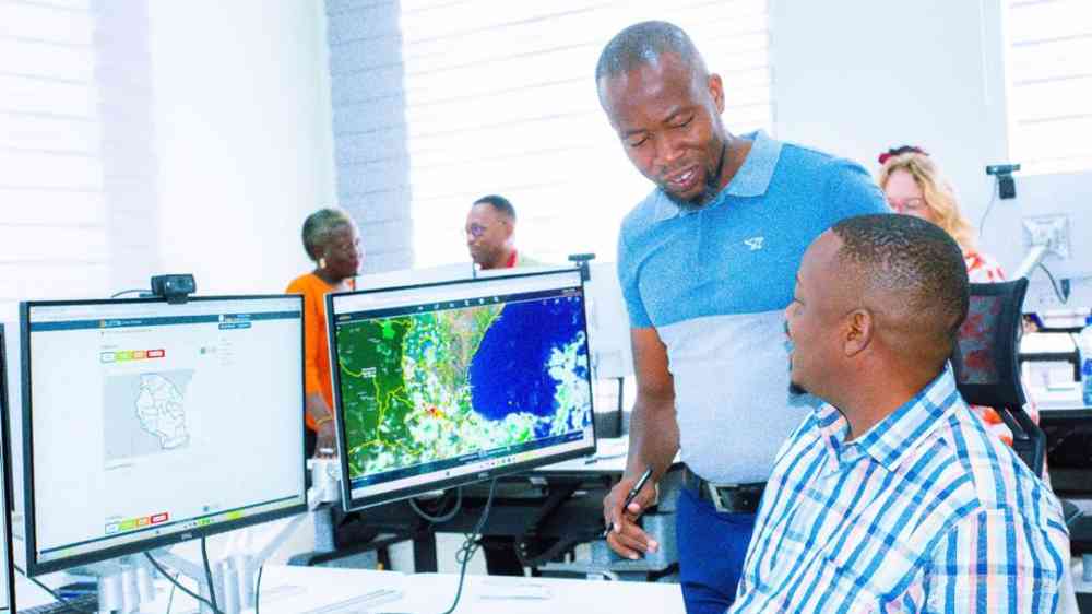 Two men talking in front of a computer in the Tanzanian Situation room