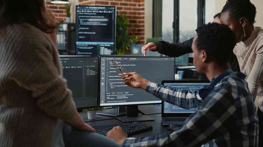 Image of three persons pointing and discussing about the data on PC screen