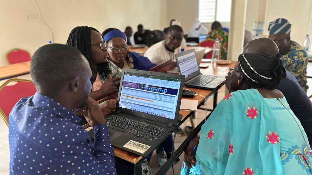Participants citing at a table around a computer showing the MCR2030 scorecard