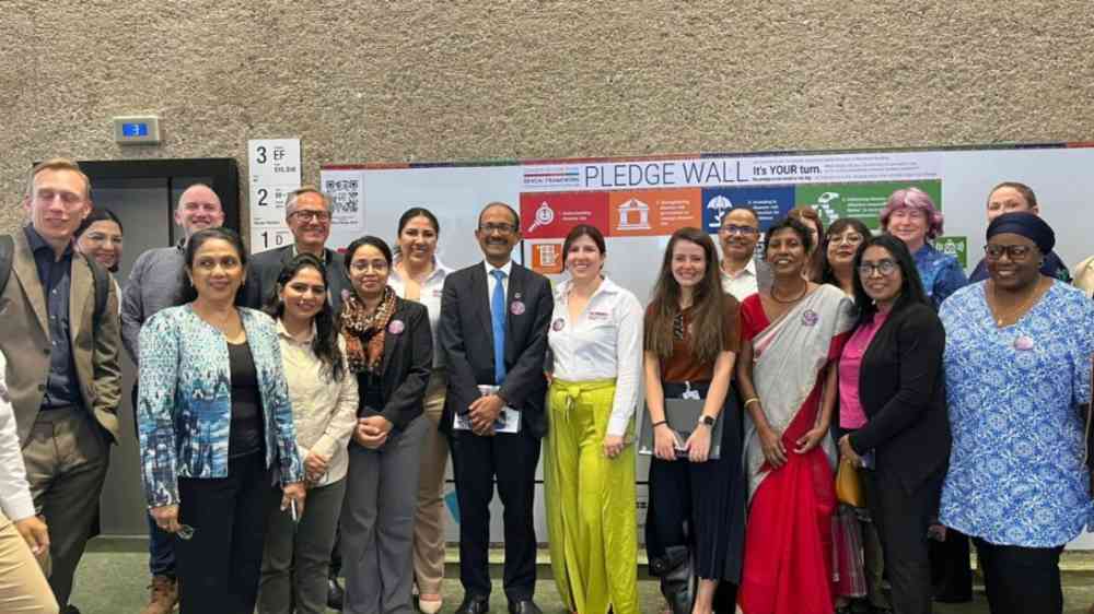 Members of the LAC Womens' Network and SRSG Kamal Kishore stand in front of a pledge wall