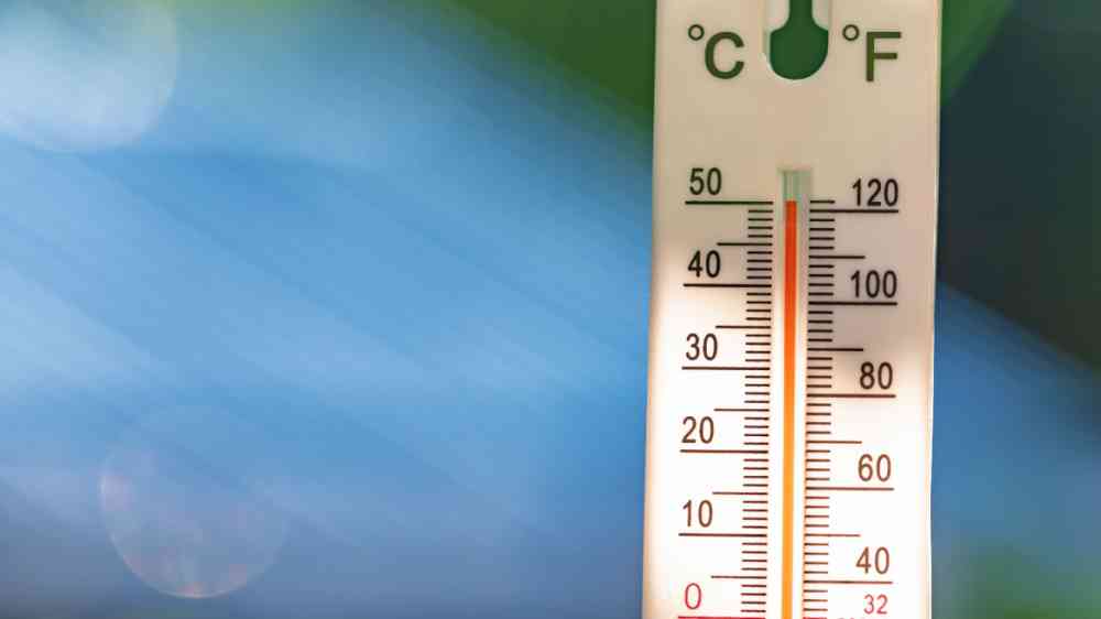 A vertical outdoor thermometer with dual Celsius and Fahrenheit scales shows a dangerously high summer temperature of 50°C.