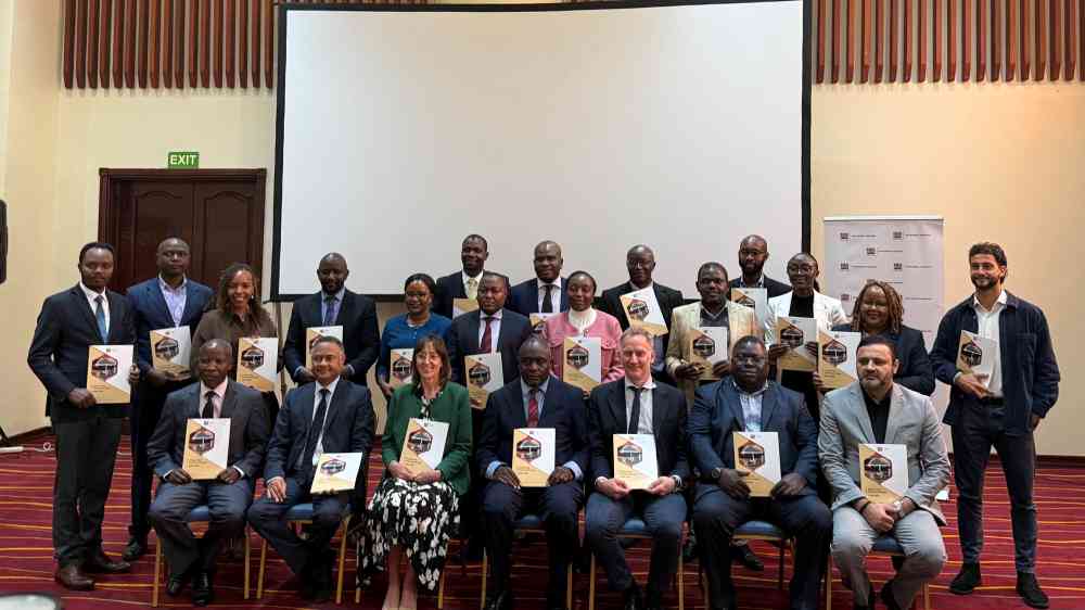 Group photo for the Kenya DRFS Launch, with everyone pictured holding a physical copy of the strategy report. The photo has been taken indoors