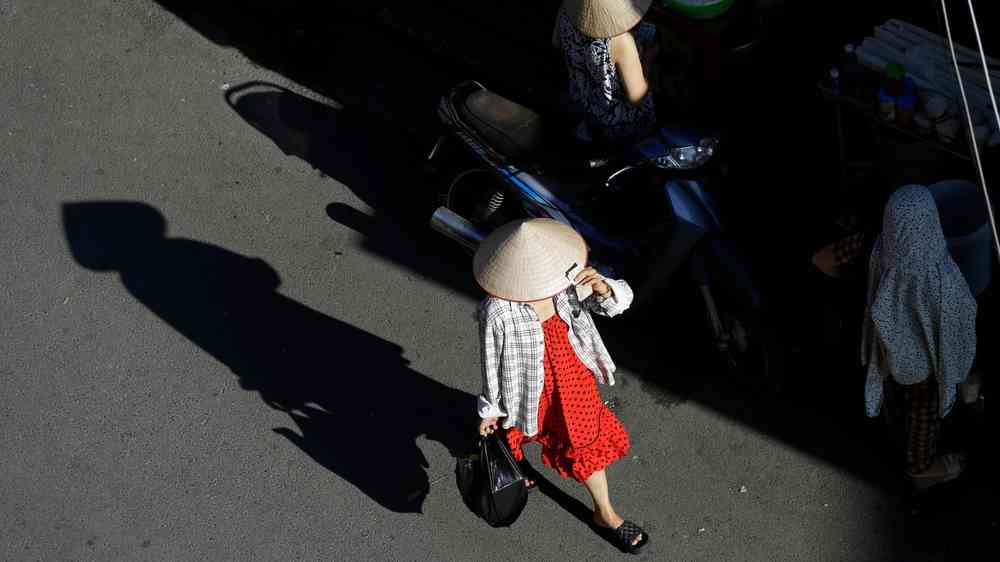Vietnamese woman wears the traditional conical hat, known as Non La, used to shield the face from the hot sun, during an extreme heat wave.