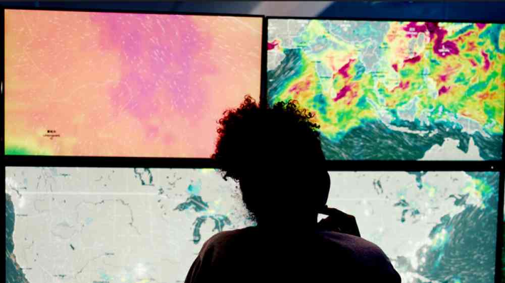 Three silhouettes in front of weather monitoring screens