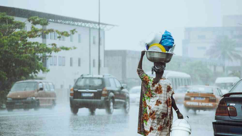 a-woman-carrying-a-bucket-on-her-head-in-the-rain