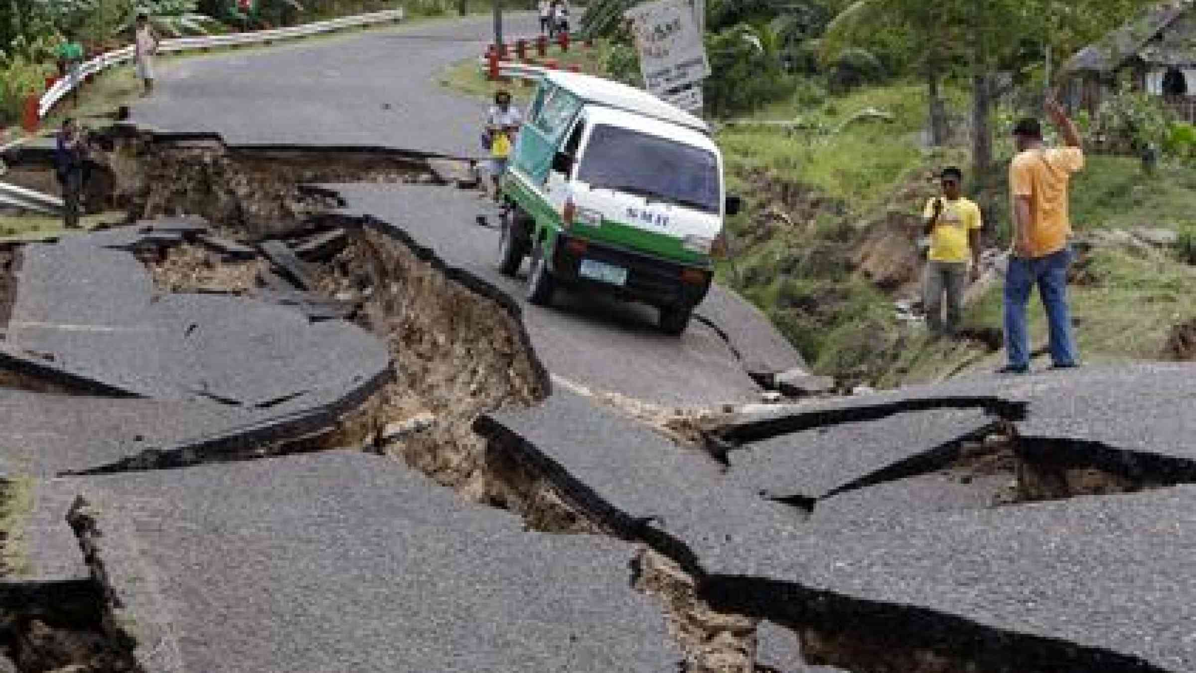 Filipinos drive past a damaged national highway after a 6.9-magnitude earthquake in Guihulngan Town, province of Negros Oriental, Central Philippines, on Feb. 7 (Dennis M. Sabangan / EPA)