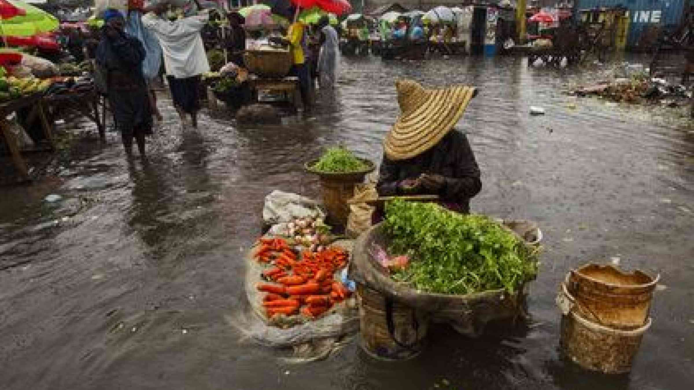 Hurricane Sandy passed to the west of Haiti on 25 October, causing heavy rains and strong winds, flooding homes and overflowing rivers. A woman sells produce at a flooded market place.