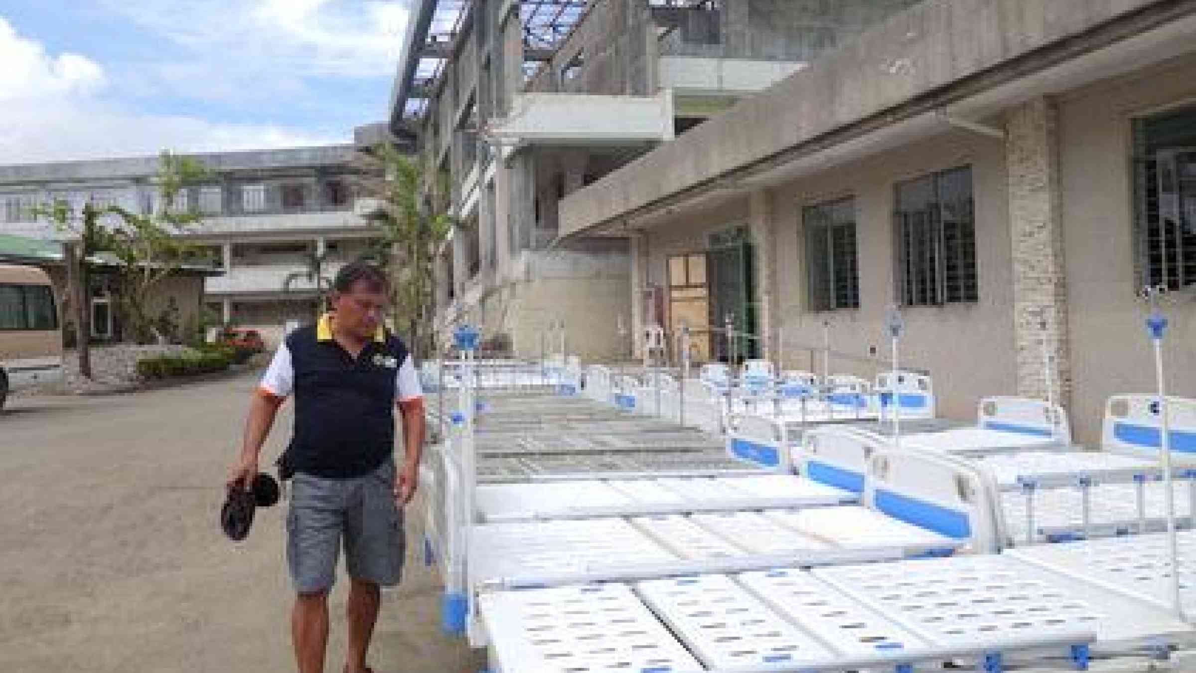 Dr. Cirilo Galindez inspects replacement beds for the flood-damaged hospital. Behind him looms the wreck of the concrete out-patients department which protected the main hospital from the worst of Typhoon Haiyan's fury.