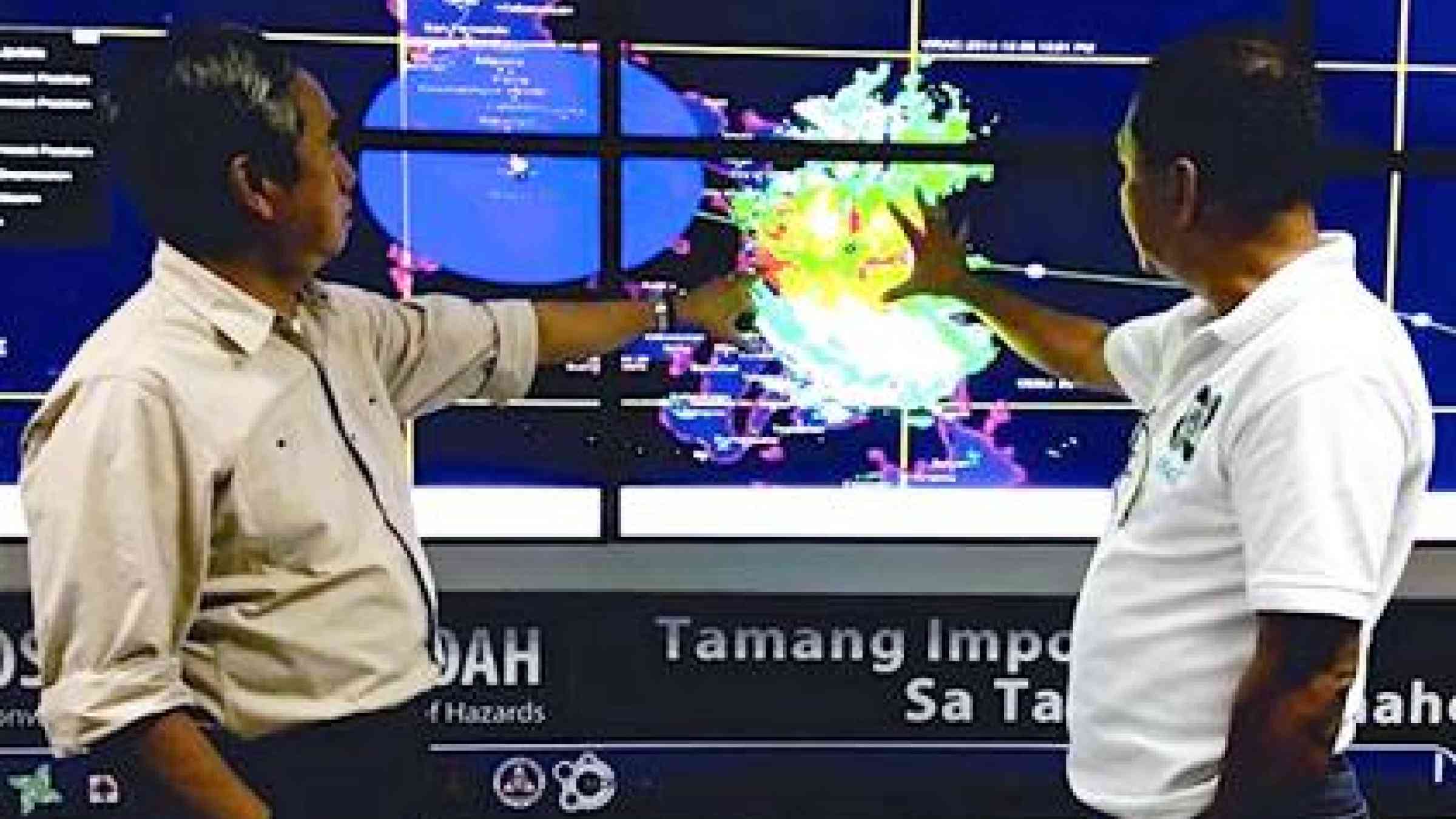 Alexander Pama (left), Executive Director of the Philippines' National Disaster Risk Reduction and Management Council, receives a briefing from a local meteorologist on the expected movement of Typhoon Hagupit. (Photo: Kenly Monteagudo)