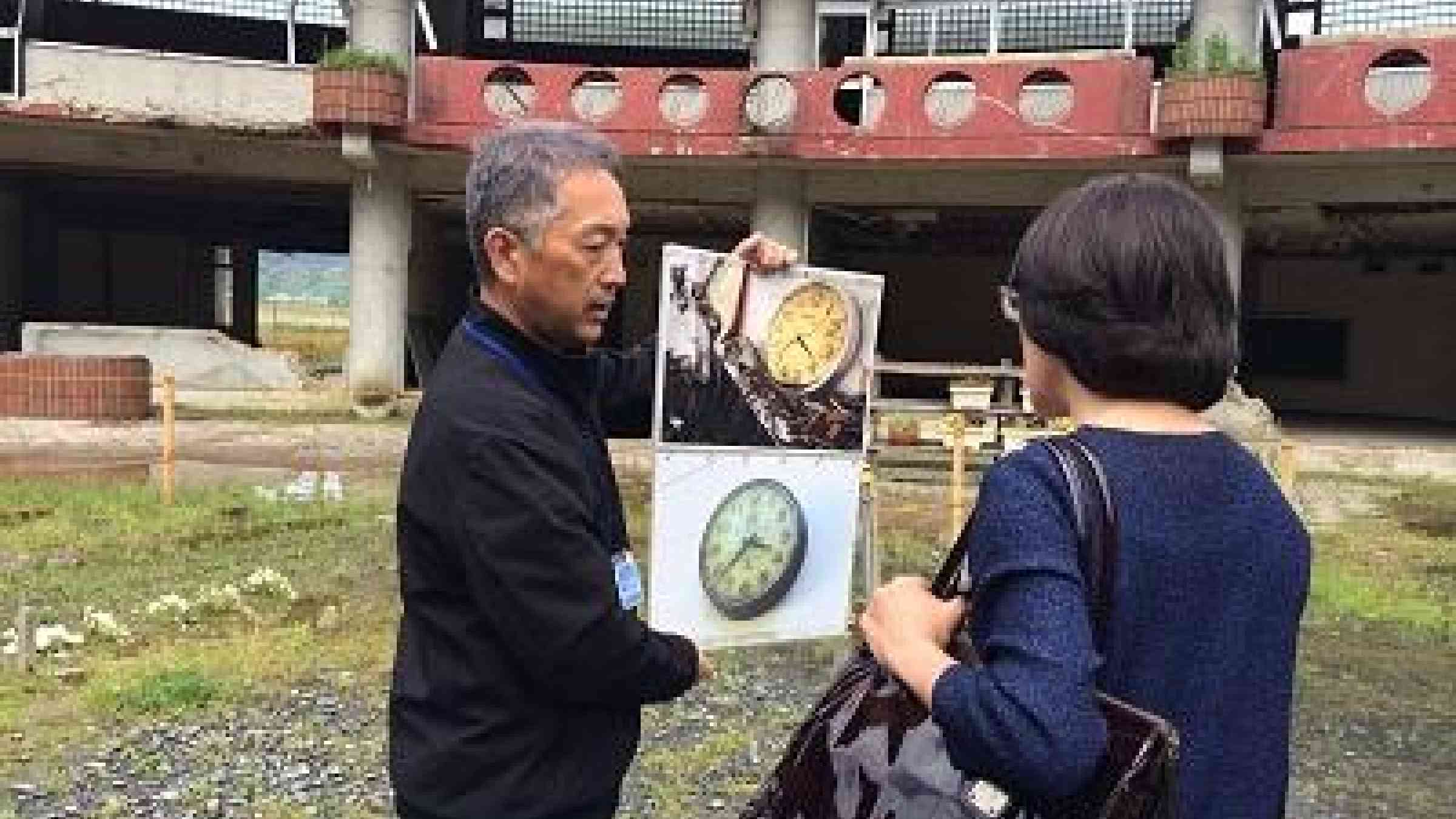 Noriyuki Suzuki who lost his daughter Mai in the 2011 tsunami shows UNISDR head, Mami Mizutori, a photo of the Okawa school clock which stopped at the time the tsunami hit. 74 children and ten teachers lost their lives at the school.