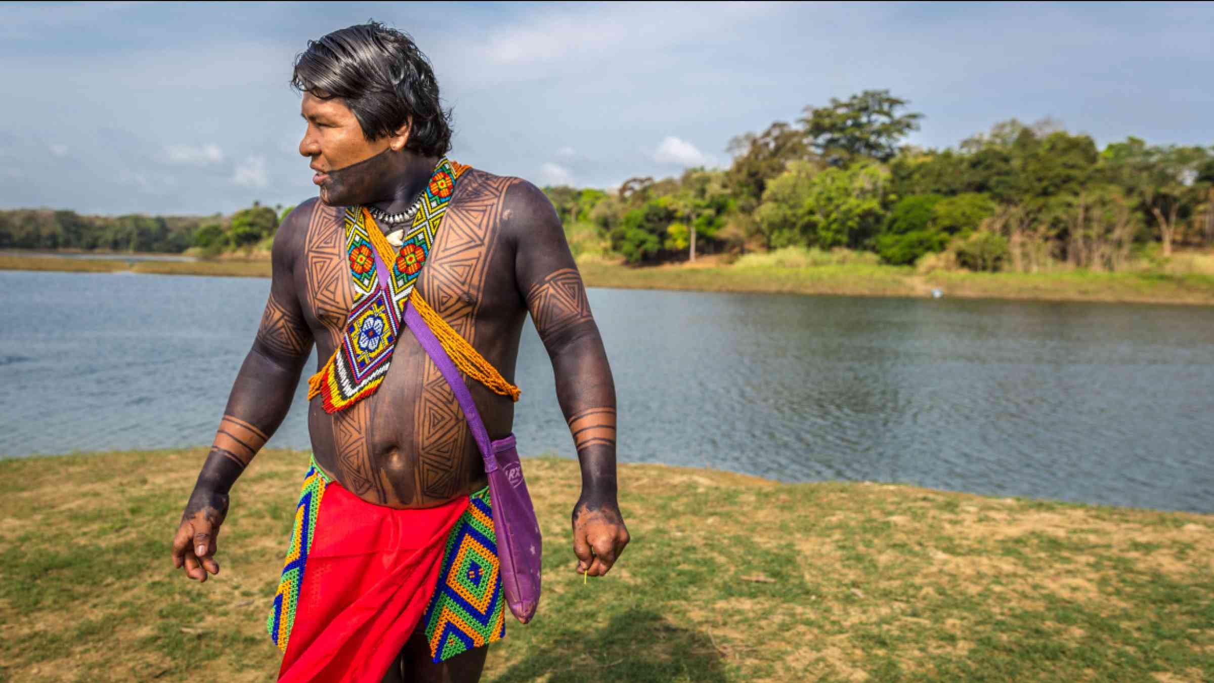 An indigenous man dressing with his traditional clothes and paints in the edge of a river at Embera Drua, Panama