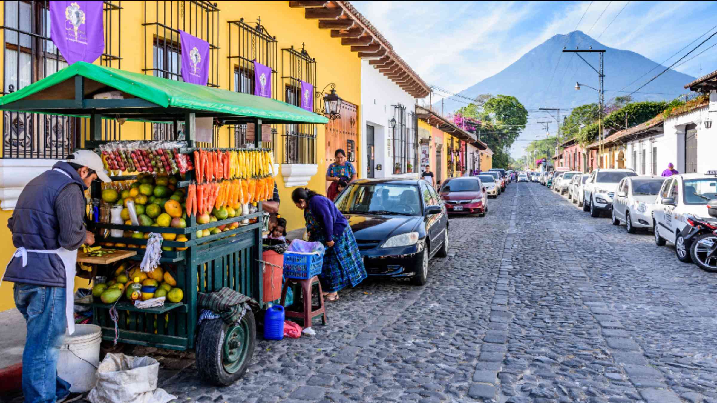 Fruit seller in front of colorful houses in Antigua Guatemala, Guatemala