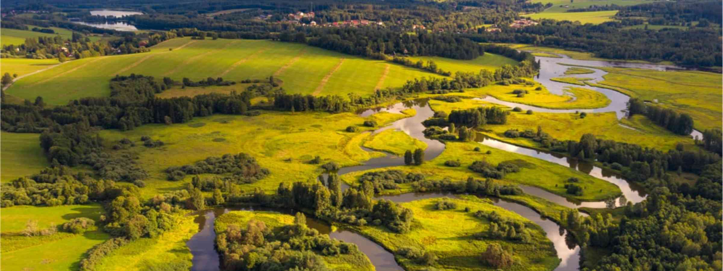 River flowing through green fields and hills.