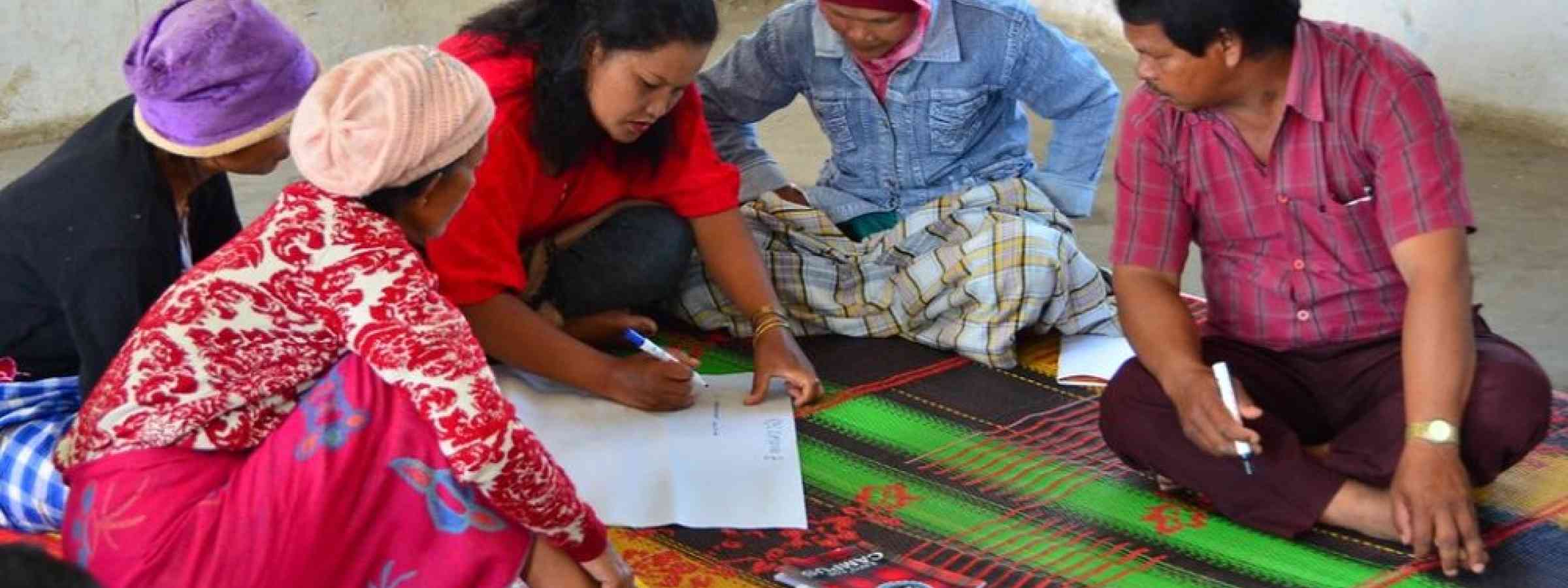 Group of people sitting on a carpet receiving training on Financial Education
