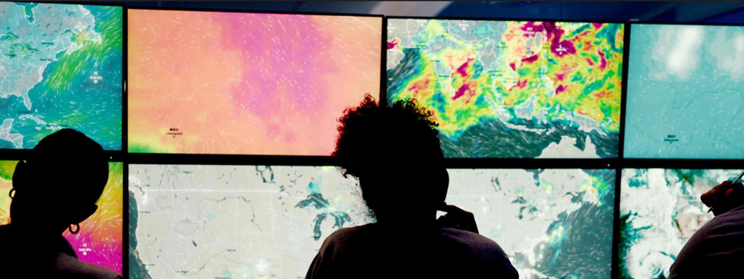 Three silhouettes in front of weather monitoring screens