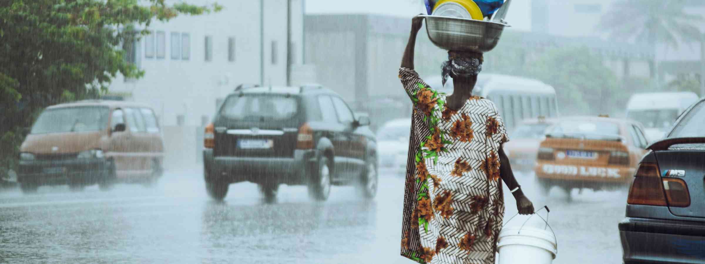 a-woman-carrying-a-bucket-on-her-head-in-the-rain